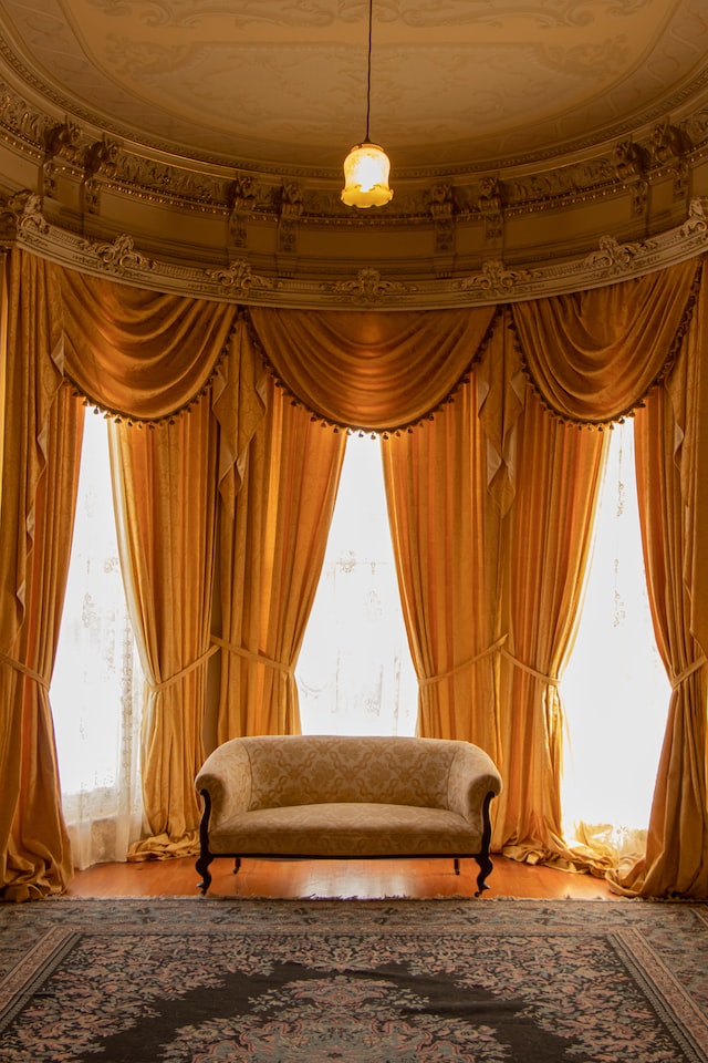 a room with a sofa and grand looking gold curtains