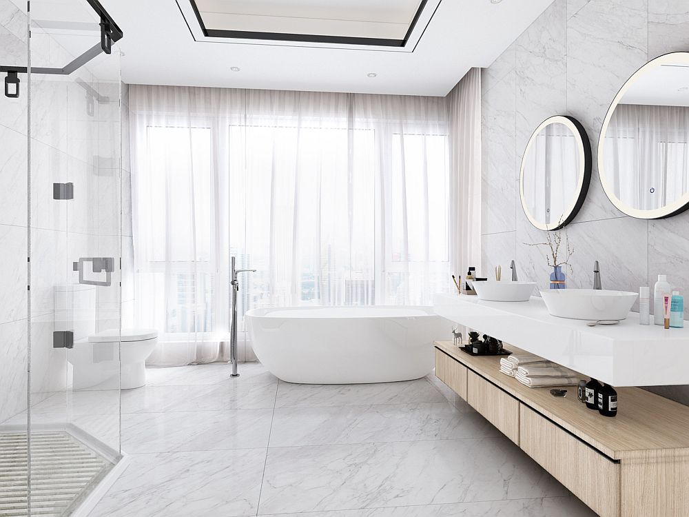 Modern bathroom with a white vanity, round mirror, freestanding tub, wooden shelves with plants, and light green walls above white tile featuring expert bathroom waterproofing.